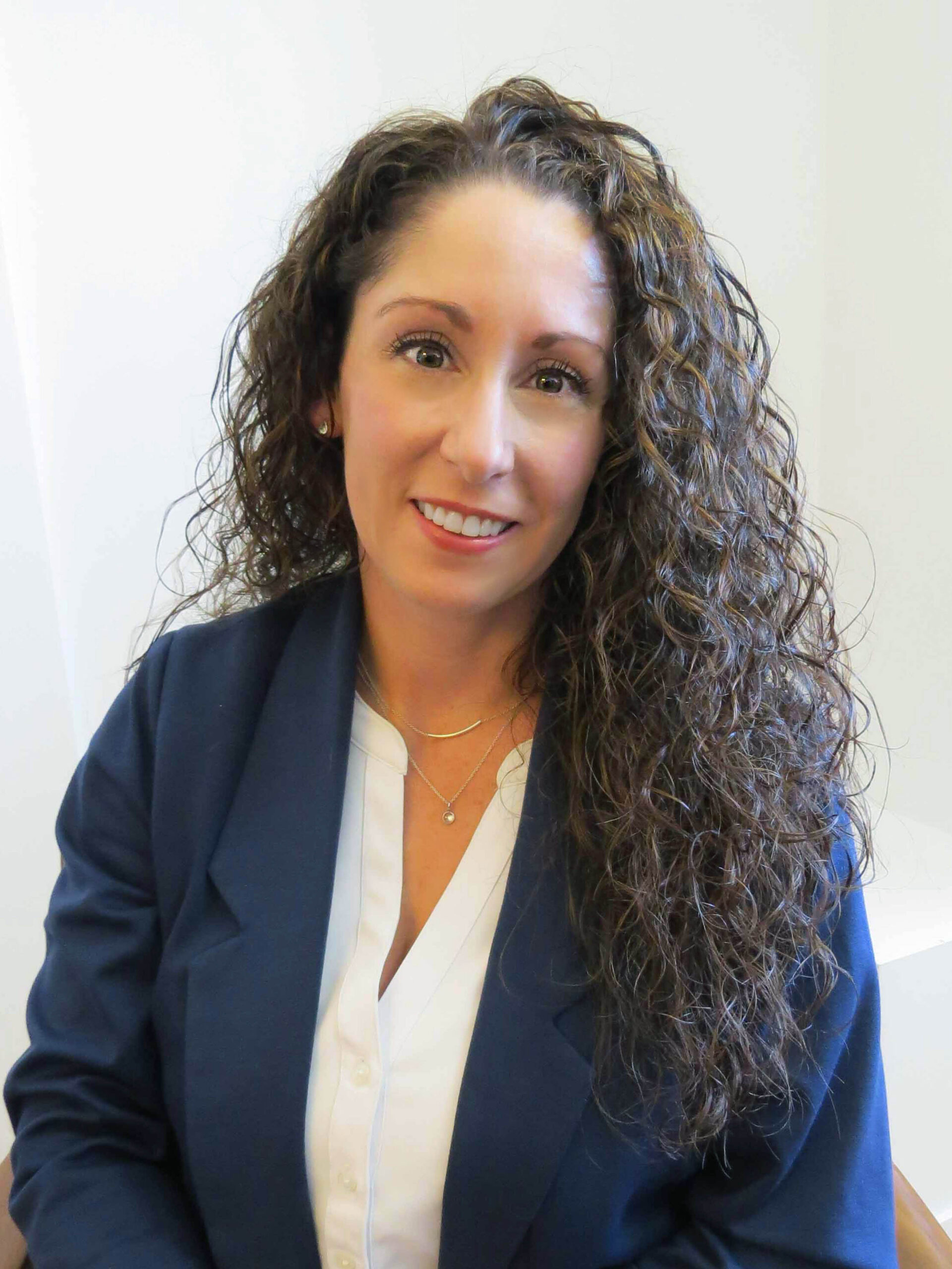 Photo of a woman with dark curly hair in a blazer